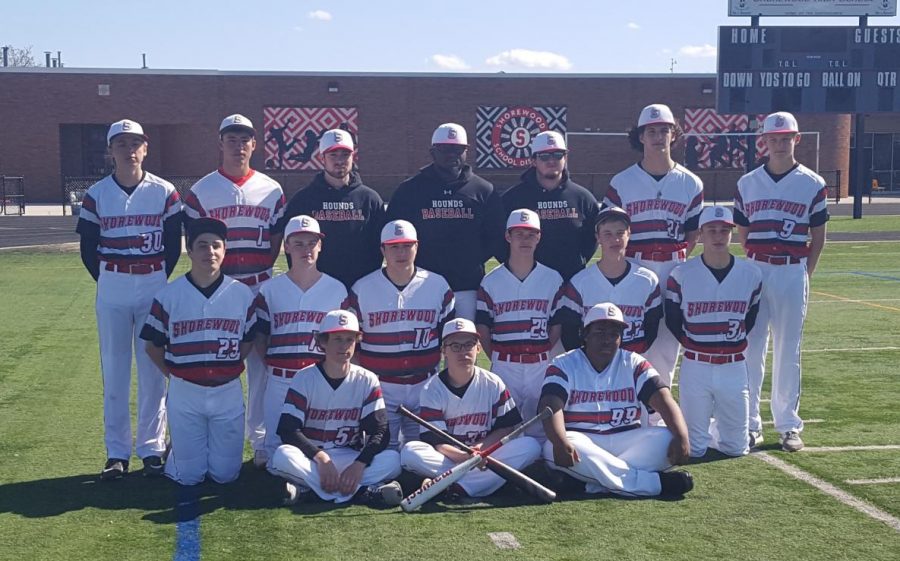 The high school varsity baseball team gathers for a team photo. The team had to overcome many challenges this year, such as low numbers and no school diamond.