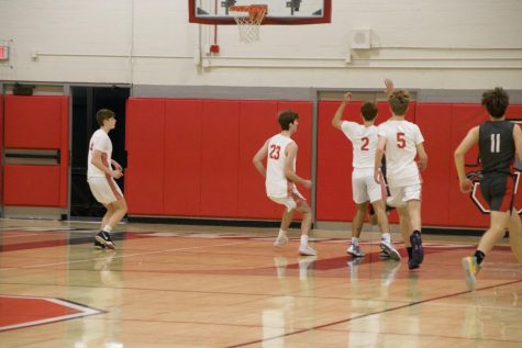 The boys basketball team plays defense during a game. The team started strong, with an early record of 2-1.